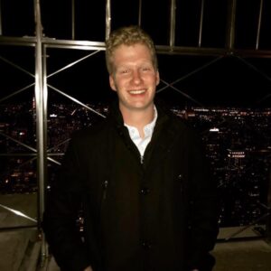 Rising senior Ethan Cummiskey is pictured in front of a nighttime cityscape.