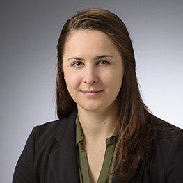 Portrait of Lauren Mello, P.E., CNU-A, wearing a black suit jacket and green collared shirt.