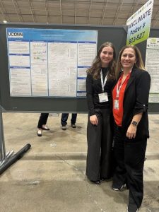 Marina Astitha (right) stands beside a student in front of a UConn research poster at a conference.